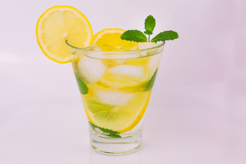 
Lemon and mint lemonade with ice cubes in a stanan on a white background. A refreshing drink. Close-up.