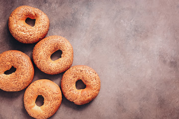 Flat lay homemade fresh bagels with sesame seeds on a dark background. Top view, copy space.