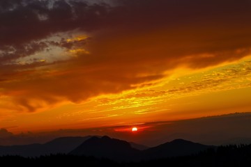 Breathtaking colorful cloudy sunrise in Big Pasture Plateau. Roadtrip in Slovenia. Silhouettes of mountains.