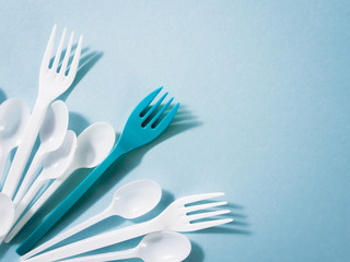 Plastic dishes, disposable tableware, plates, glasses, spoons, forks on a blue background. Caring for the environment. The problem is recycling. Reuse, safe planet, environmental concept. Trash.