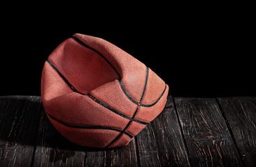 Deflated and rumpled old ball on a wooden floor