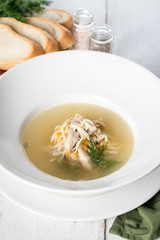 Chicken soup in a white rough plate served with bread