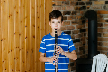 Boy with a clarinet plays music. Online music lesson concept - obrazy, fototapety, plakaty