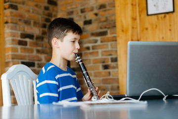 Boy with a clarinet plays music. Online music lesson concept - obrazy, fototapety, plakaty