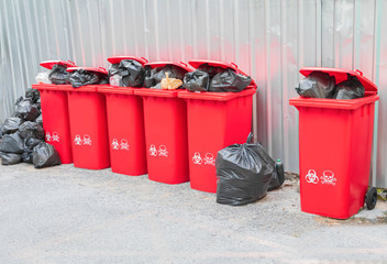 group red bins six with symbol infectious and  garbage bag black pile On top in the outdoors....
