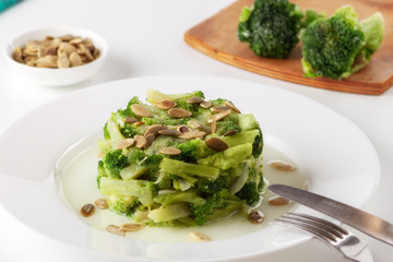 Boiled broccoli with pumpkin seeds on a white plate on the table