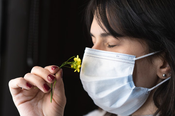 mujer oliendo una flor con un barbijo en cuarentena woman smelling a flower with a chin mask