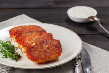 Potato pancakes with sour cream and dill on a wooden table