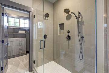 Natural new classic slick bathroom interior with new glass walk in shower, white tub and walk in...
