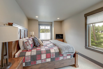 Natural tone luxury bedroom interiors in new American vacation home. Wood furniture and beige carpet.