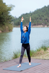 A young Asian woman practicing yoga in the outdoors