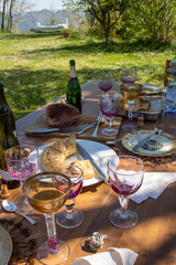 A table with the remains of a festive easter lunch in the italian countryside. Silverware and crockery, remains of delicious food, empty wine bottles. Satisfaction concept.