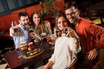 Handsome young friends making selfie and smiling while having a dinner in restaurant