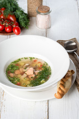 Fish soup with fresh herbs and bread served in a white plate