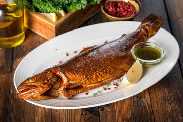 Smoked trout served with sauce, lemon on a white plate