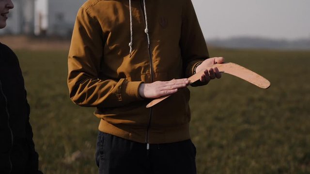 young couple in love together launch a boomerang in a field