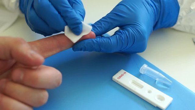 Taking a blood test for coronovirus covid-19 in a laboratory. Processing a finger with a disinfectant wipe. Rapid test covid 19