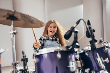Obraz na płótnie Canvas teenage girl playing drums in music studio