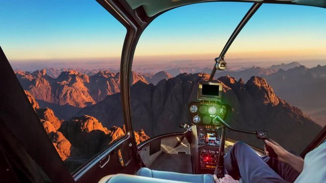 Helicopter cockpit with pilot arm and control console inside the cabin in aerial view of the holy summit of Mount Sinai, Aka Jebel Musa, 2285 meters, at sunrise, Sinai Peninsula in Egypt.