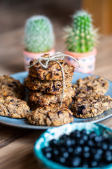 Set of easy to prepare and healthy, homemade oatmeal and blueberry cookies - on beautiful blue plate. Cookies are tied and decorated with string. Bowl full of blueberries next to it.