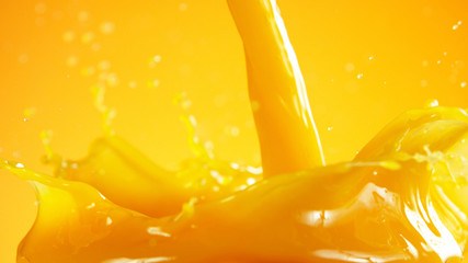 Orange juice splash on coloured background