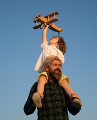 Fathers day. Father and son. Boy with toy aeroplane sitting on father's shoulders on sky.