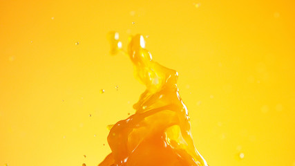 Orange juice splash on coloured background