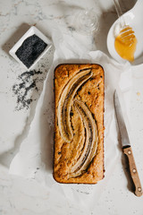 Butter-free, sugar-free banana bread with oat flour, soft curd cheese and honey. Top view of sliced banana bread on gray marble background. Ideas and recipes for healthy diet breakfast