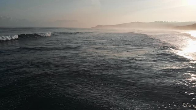 Northern Spain. Waves of Atlantic Ocean rolling to the shore. Evening sun reflecting on water. Aerial shot, 4K