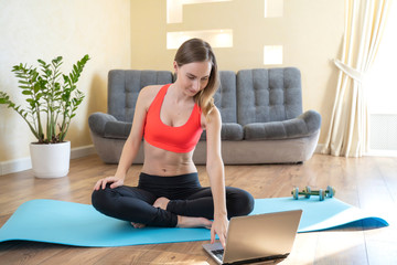 Fototapeta na wymiar Portrait of fit woman training in her living room with laptop