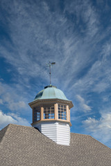 A classic cupola under clear blue skies topped by a weather vane