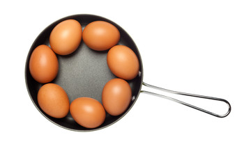 Frying pan with seven eggs arranged in a ring isolated on white background; 

