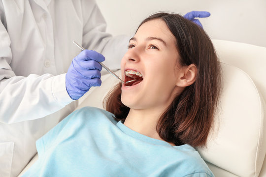 Teenage Girl With Dental Braces Visiting Orthodontist In Clinic