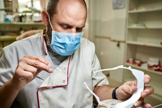 Technician Developing A Prototype Of A Face Mask For Protection Against Corona Virus, Removing The Plastic Protection.