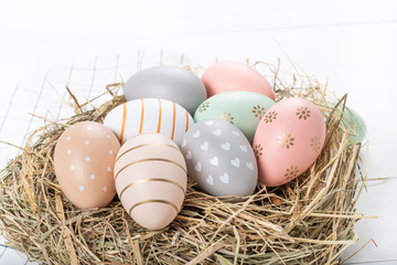 Easter table setting, holiday table home decor idea, flat lay composition with white plates, cutlery, colorful pastel painted Easter eggs, festive decor and fresh spring flowers