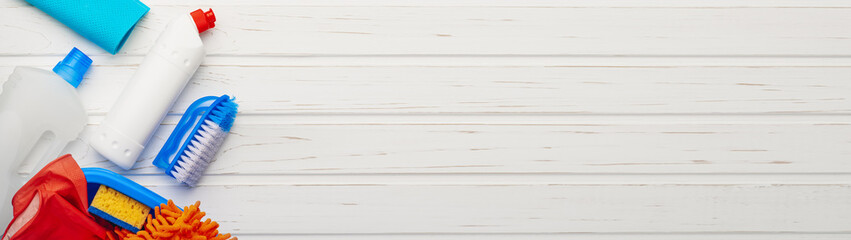 Variety of cleaning products on wooden white background web banner with copy space: spring cleaning...