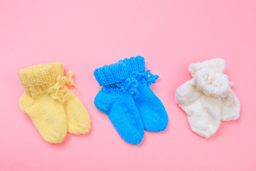 knitted baby booties on pastel pink background.