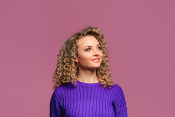 beautiful young woman   with curl hair in knitted violet sweater posing   on pink   background  - Image