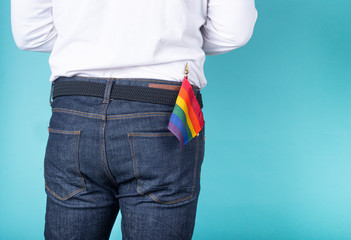 Man from the back with LGBT pennant in the pocket of jeans on a blue background.