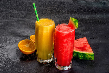 Fototapeta na wymiar Two fresh watermelon and orange fresh on a black background with splashes