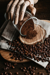 Bodegón de café con una copa y una mano sobre un trapo.
Rodaja de madera y grano de café