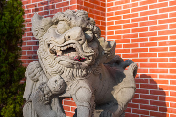 Lion stone statue in front of the Hung Shing Temple (Mui Wo, Lantau Island, Hong Kong, China). Beautiful close up of this dominant animal figure. It has incense sticks in its mouth. 