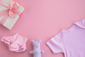 Newborn baby girl accessories. Clothes bodysuit, pair of small socks, gift box and toy on pink...