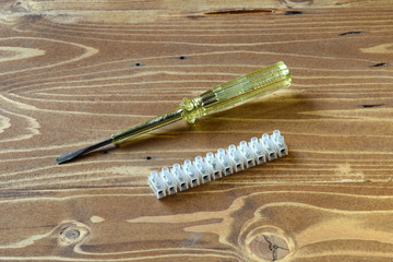 The electric voltage indicator screwdriver and the terminal block are on the wooden table