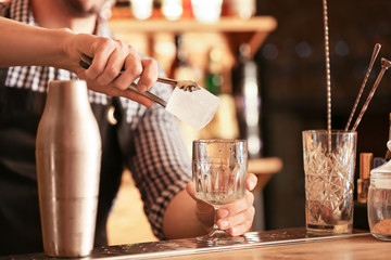 Male bartender making cocktail in pub