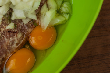 Minced meat in green pot with egg and onion on table.Tasty food