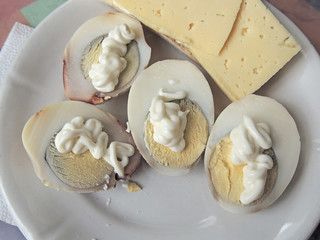 boiled egg in a composition with cheese and mayonnaise on a white plate.