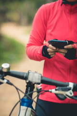Obraz premium Cyclist use smartphone for navigation when riding mountain bike on forest trail