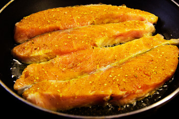 Salmon fillet is fried in olive oil on the cooking pan. Fresh salmon - seafood
