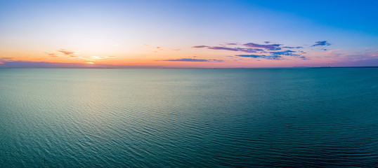 Fototapeta na wymiar Wide aerial panorama of sunset over ocean with copy space